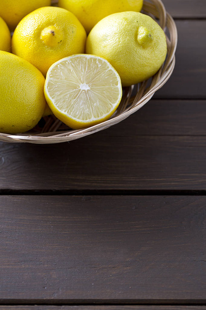 lemons in basket on brown wooden surface - Zdjęcie, obraz