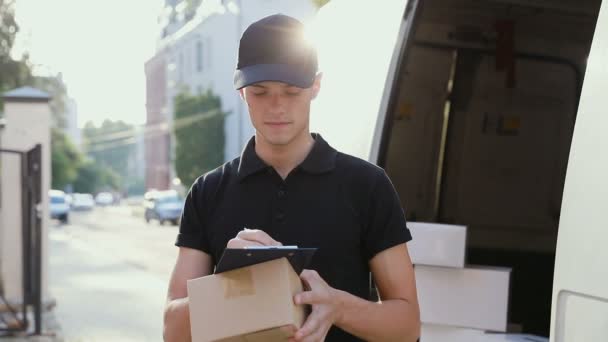 Delivery Service. Courier With Box In Hands Near Car Outdoors - Materiał filmowy, wideo