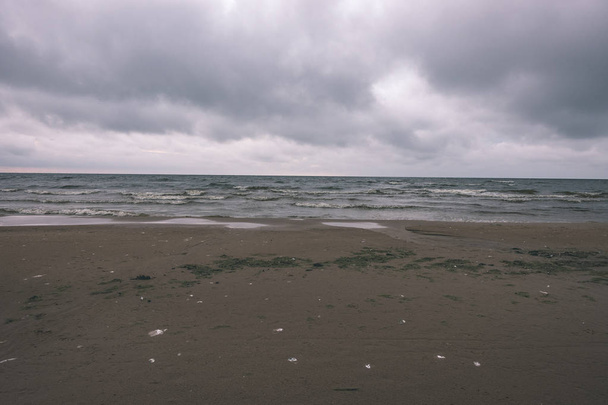 темная морская вода и пляж под бурным небом
 - Фото, изображение