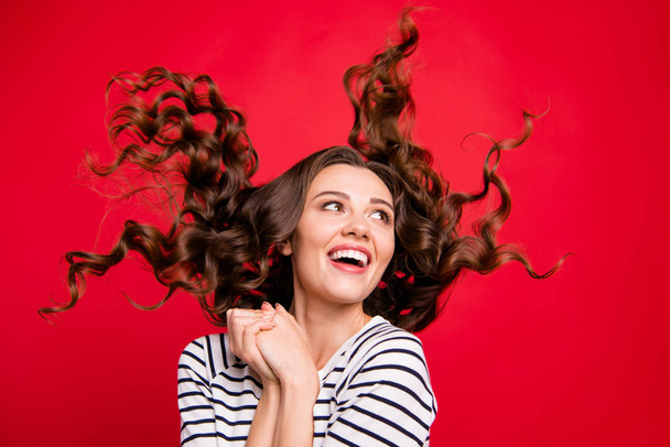 Close up  portrait of in delight satisfied glad attractive she her girl arms together hair flies watching top of empty space wearing white striped casual sweater on red vivid bright background - Foto, Imagem