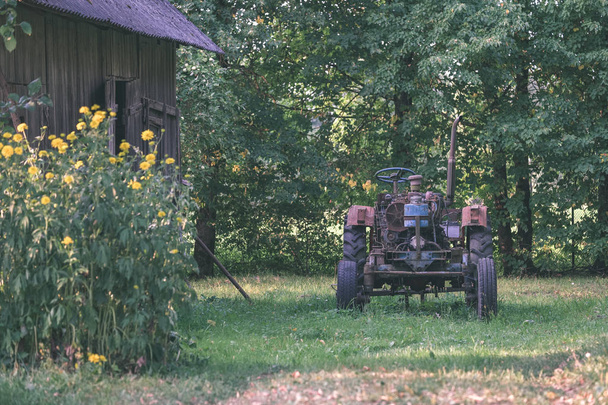viejo tractor con neumáticos de goma en el patio verde del campo
 - Foto, Imagen