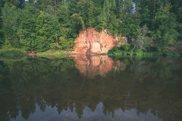 sandstone cliffs on shores of river Amata and green woods, Latvia - Foto, afbeelding