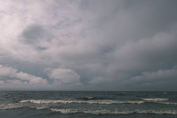 темная морская вода и пляж под бурным небом
 - Фото, изображение