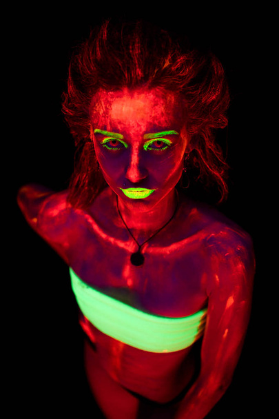 Portret pięknej młodej dziewczyny sexy ultrafioletowe farby na jej ciało. Ładna kobieta z świecące ultrafioletowe w czarny Lampa światło - Zdjęcie, obraz