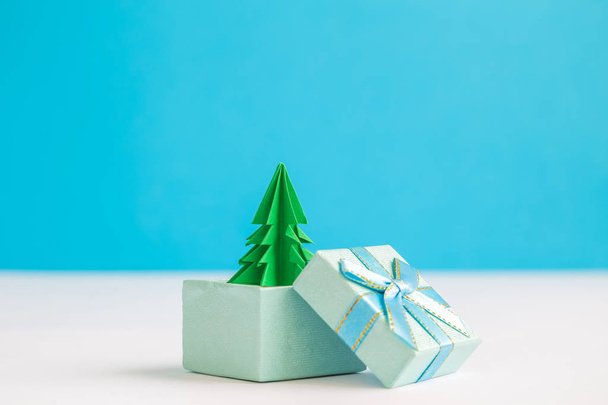 Christmas tree in gift box against pastel blue background minimal creative holiday concept. Space for copy. - Fotoğraf, Görsel