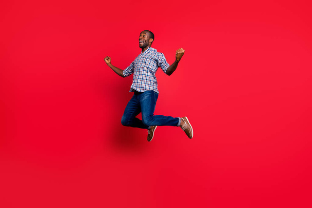 Full length body size portrait of nice funny handsome cheerful positive guy wearing checkered shirt showing winning gesture party in air isolated on bright vivid shine red background - Foto, afbeelding