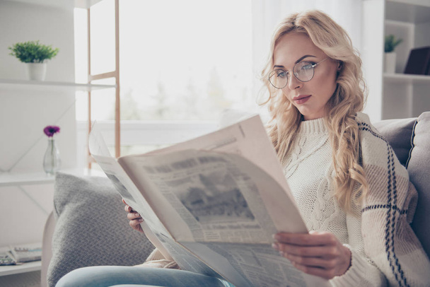 Portrait of nice adorable attractive intelligent wavy-haired lady housewife wearing sweater holding in hands reading interesting digest in light interior room - Photo, image