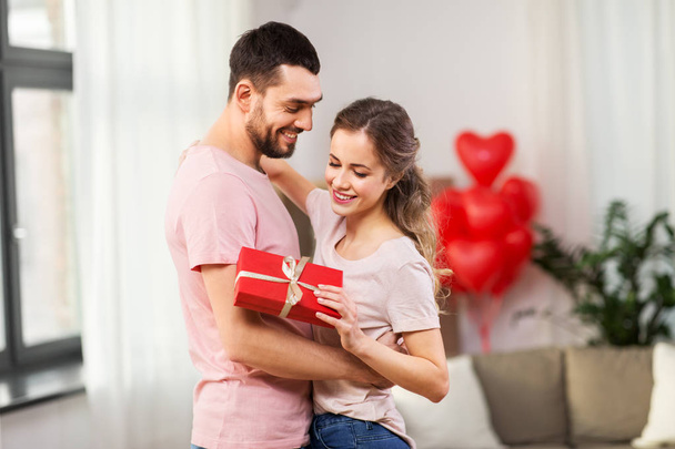 happy couple with gift box hugging at home - Фото, зображення