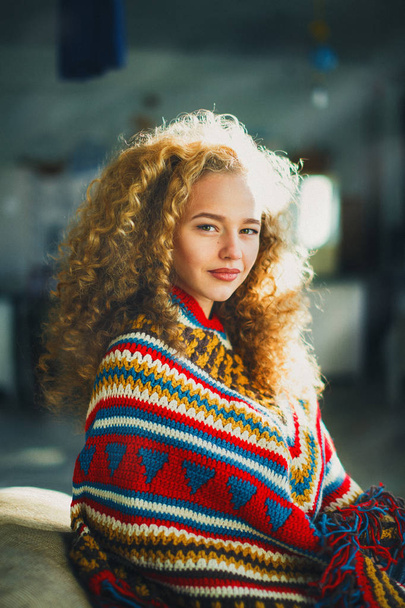 Beautiful curly girl sitting in a poncho - Foto, imagen