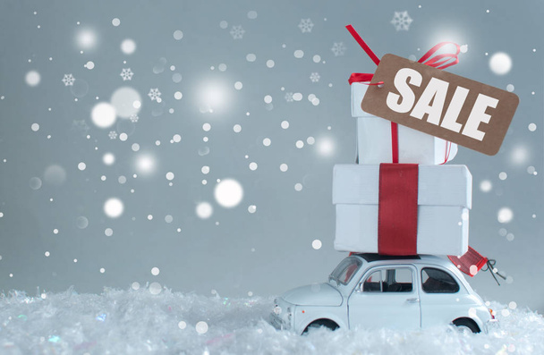 Gift boxes stacked on top of a retro car with sale sign - 写真・画像