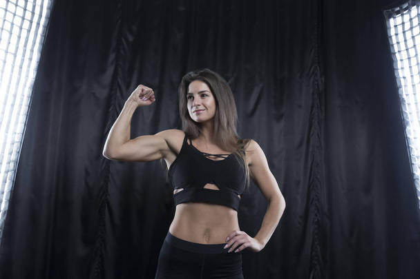 Fitness model in black sports uniform posing on a dark background - Photo, Image
