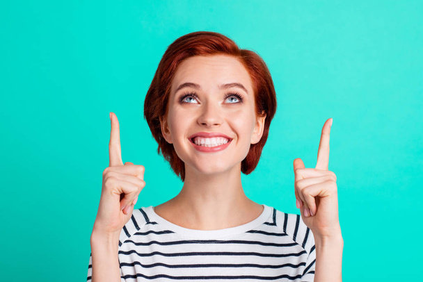 Close-up portrait of nice lovely sweet charming winsome attractive cheerful red-haired lady in striped pullover pointing two forefingers up isolated over bright vivid shine green turquoise background - Fotó, kép