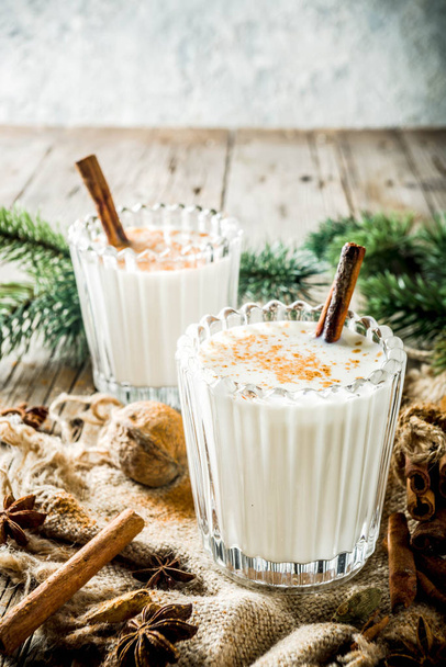 Bebida clásica de Navidad Eggnog, cóctel chileno Cola de mono (cola de mono), o ponche de huevo puertorriqueño Coquito, sobre fondo de madera vieja con ramas de pino copiar espacios
 - Foto, imagen