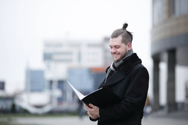 бизнесмен читает документы, стоящие на городской улице
. - Фото, изображение