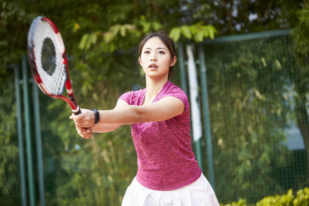 young asian woman playing tennis outdoors - Foto, afbeelding