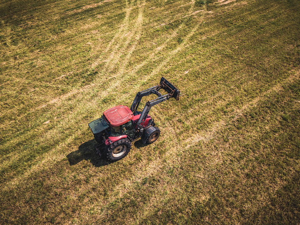 Редагувати Drone антена фото фермер заготівлі сіна рулонів в пшеничному полі з червоним трактор - Vintage вигляд, Сонячний літній день - Фото, зображення