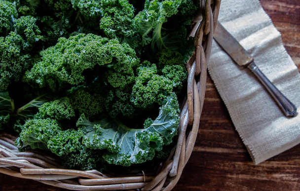 Vihreä Kale korissa ja veitsi puinen tausta ylhäältä näkymä päivänvalossa superruoka vihanneksia Asetelma
 - Valokuva, kuva