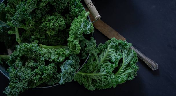 Couve verde e faca no fundo preto vista superior sobre a luz do dia superfood legumes Natureza morta
 - Foto, Imagem