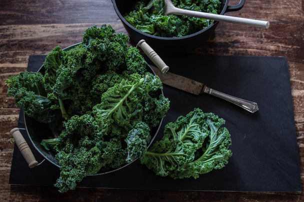 Cavolo verde e coltello su sfondo nero vista dall'alto sulla luce del giorno verdure superfood Natura morta
 - Foto, immagini