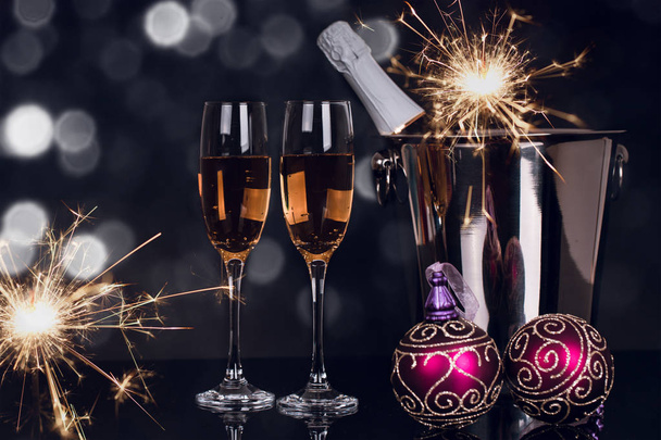 シャンパン、ボトル、花火、黒い背景にクリスマスの飾りを 2 つのワイングラス。領域をコピーします。メリー クリスマスと新年あけましておめでとうございます、背景 - 写真・画像