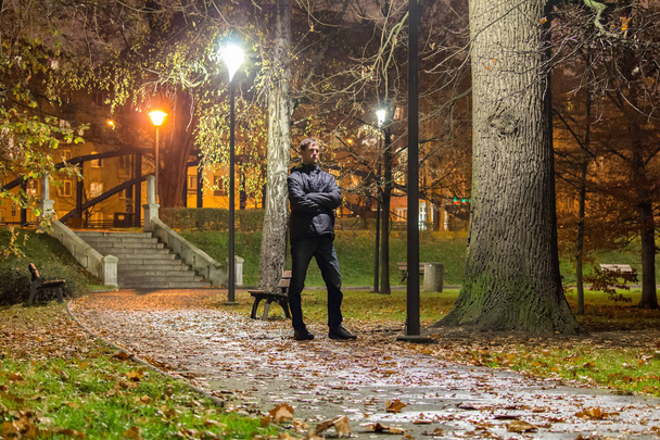 Retrato de jovem de pé na rua no parque da cidade à noite
 - Foto, Imagem