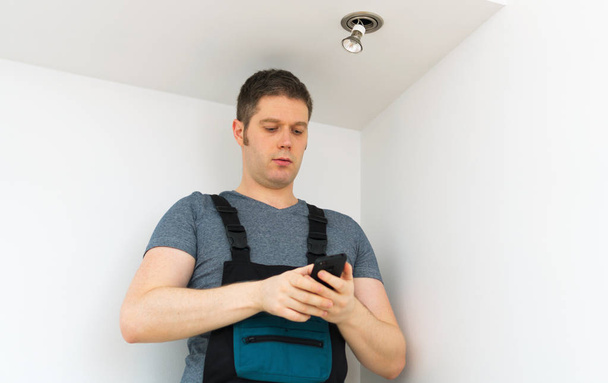 Electricista certificado comprobando la luz inteligente de la casa a través de smartphone
. - Foto, imagen