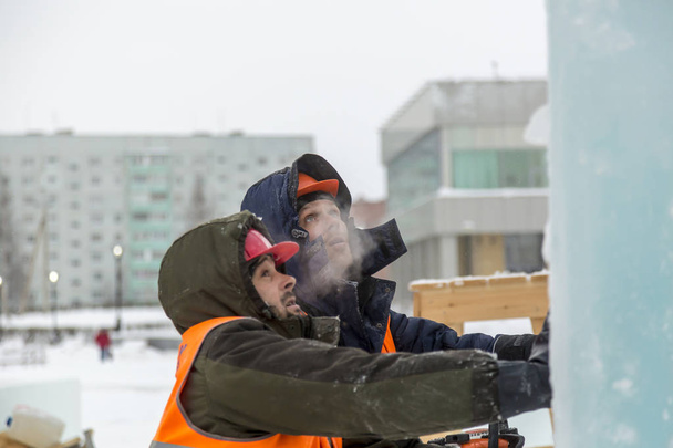I lavoratori costruiscono una città di ghiaccio dai blocchi di ghiaccio per le vacanze di Natale - Foto, immagini