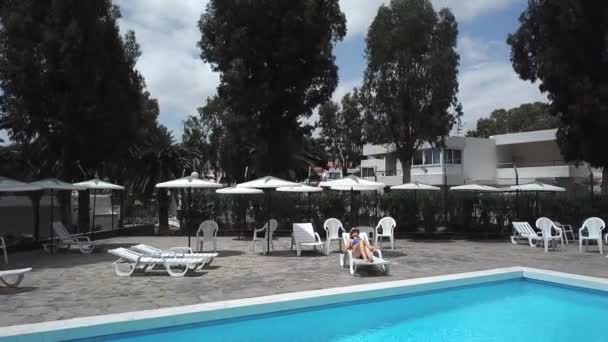 Bir tembel bir otel, bir villa veya bir daire havuz kenarında üzerinde mavi bir mayo bir kadın olarak üstten görünüm sunbathes - Video, Çekim