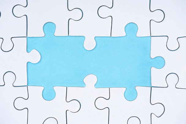 top view of white puzzles arrangement on blue background - Foto, Imagen