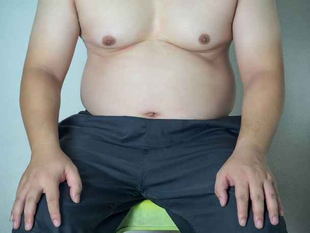 Partie du corps de gros homme asiatique avec un gros ventre assis sur une chaise
 - Photo, image