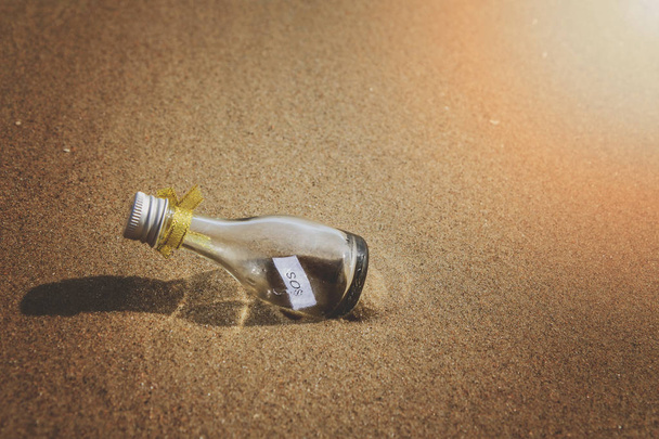 SOS μήνυμα σε γυάλινο μπουκάλι στην παραλία. - Φωτογραφία, εικόνα