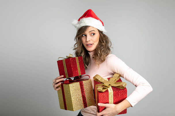 nice cute woman with christmas hat trying to hide with some gifts and smiling - Fotoğraf, Görsel