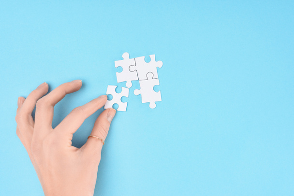 partial view of woman with white puzzles pieces on blue background - Photo, Image