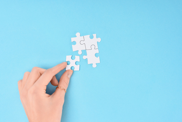 cropped shot of woman with white puzzles pieces on blue background - Photo, Image