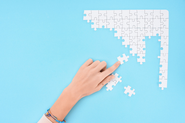 partial view of woman with white puzzles pieces on blue background - Фото, зображення