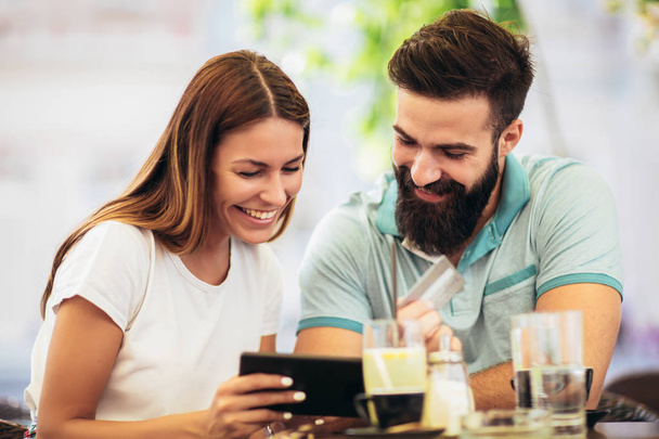 Hermosa pareja tomando café en una cita, usando tableta digital y tarjeta de crédito para compras en línea - Foto, imagen