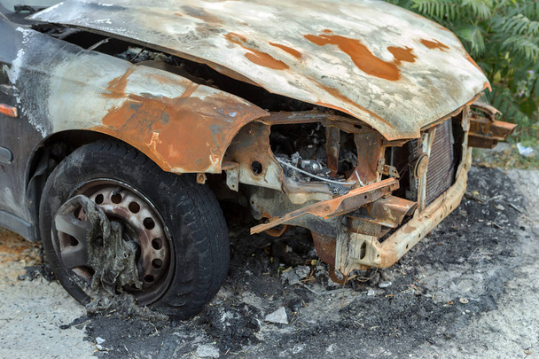 Останки сожжённого тела машины выброшены на улицу. Гражданские беспорядки в Украине в 2016 году. Массовый поджог автомобилей противников победившего режима в перевороте
. - Фото, изображение