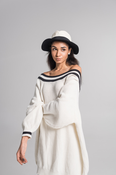 attractive african american girl in stylish white sweater and hat looking away isolated on white - Fotoğraf, Görsel