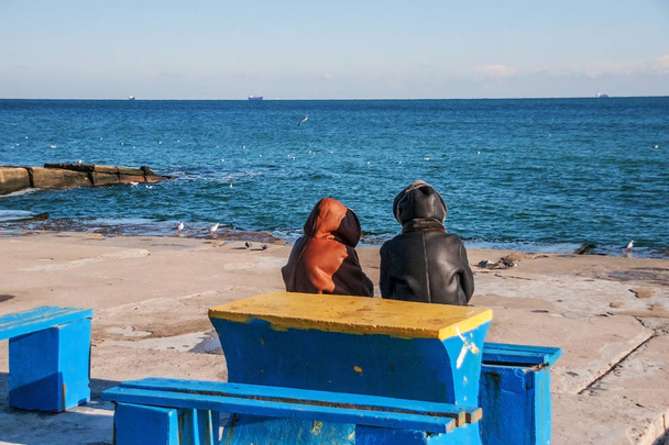 Vue arrière de deux femmes âgées tristes assises sur un banc regardant la plage et à l'horizon par une journée d'hiver claire et ensoleillée. Contexte du problème social de la vieillesse et de la solitude
 - Photo, image