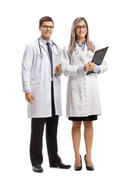 Ganzkörperporträt einer Ärztin und eines Arztes, die auf weißem Hintergrund in die Kamera lächeln - Foto, Bild