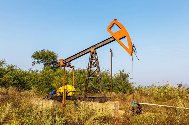 Malé soukromé ropný vrt čerpadla ropy na hřišti. Staré řemeslné ropné plošiny v pozadí kreativní průmyslového designu. Ilegální vývoj minerálů. Bulharsko Tyulenovo, 2016 - Fotografie, Obrázek