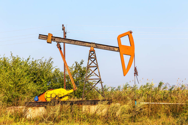 Malé soukromé ropný vrt čerpadla ropy na hřišti. Staré řemeslné ropné plošiny v pozadí kreativní průmyslového designu. Ilegální vývoj minerálů. Bulharsko Tyulenovo, 2016 - Fotografie, Obrázek