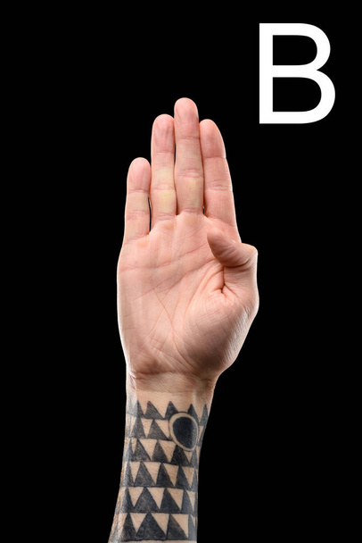 tattooed male hand showing latin letter - B, sign language, isolated on black - Фото, изображение
