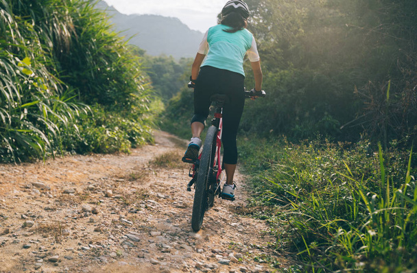 Woman cyclist riding a bike on a nature trail in the mountains. Healthy lifestyle concept - Fotó, kép