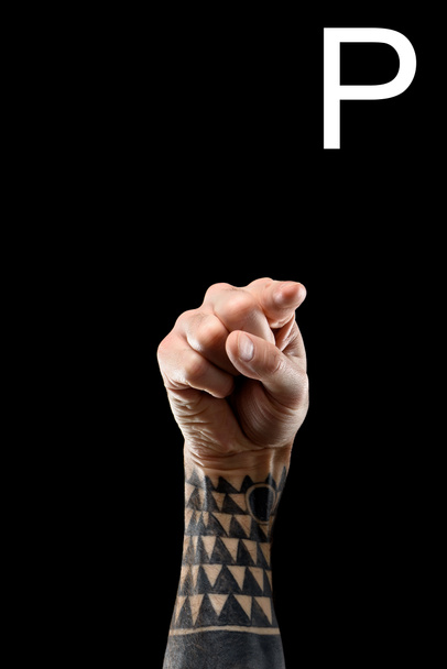 cropped view of tattooed hand showing latin letter - P, sign language, isolated on black - Photo, Image