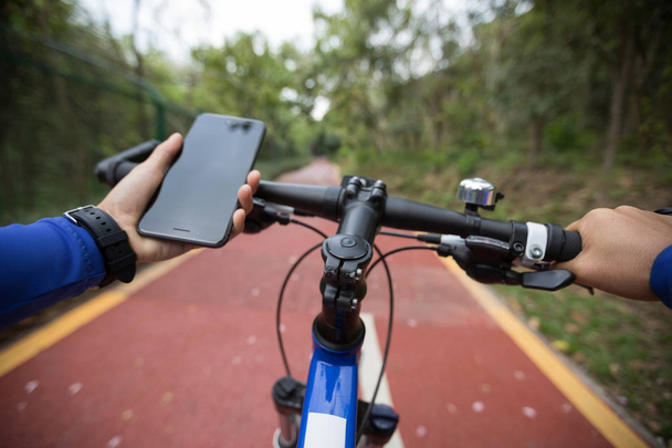 Radfahrer nutzt Smartphone-App zur Navigation während Radtour auf dem Waldweg - Foto, Bild