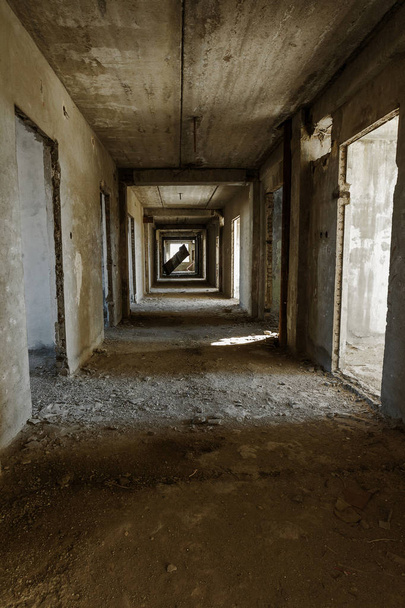 Интерьер заброшенного административного здания. Внутренние руины промышленного завода. Старая бетонная лестница, руины, коридор с мусором и грязью, разрушенные стены незавершенного офисного бизнес-центра, Одесса
 - Фото, изображение