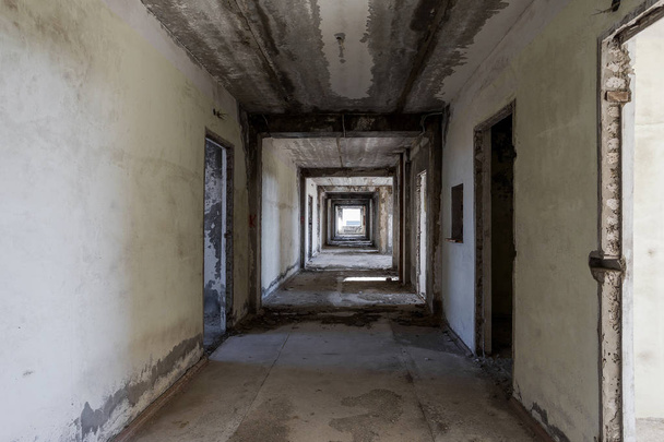 Interior de un edificio administrativo abandonado. Ruinas interiores de una fábrica industrial. Una vieja escalera de hormigón, ruinas, pasillo con basura y barro, paredes arruinadas de un centro de negocios de oficinas sin terminar, Odessa
 - Foto, Imagen