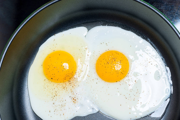 jajecznicę z dwóch jaj, smażone na patelni bliska widok z góry - Zdjęcie, obraz