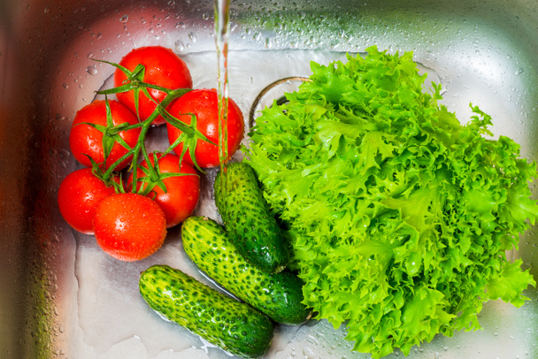 cetrioli di verdure fresche, pomodori e insalata nel lavandino in cucina
 - Foto, immagini